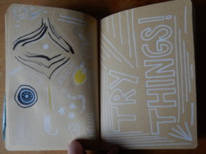 Cahier. Sur la page de gauche, on peut voir des doodles (petits dessins). Sur la page gauche, on peut lire « Try things » avec des lignes.