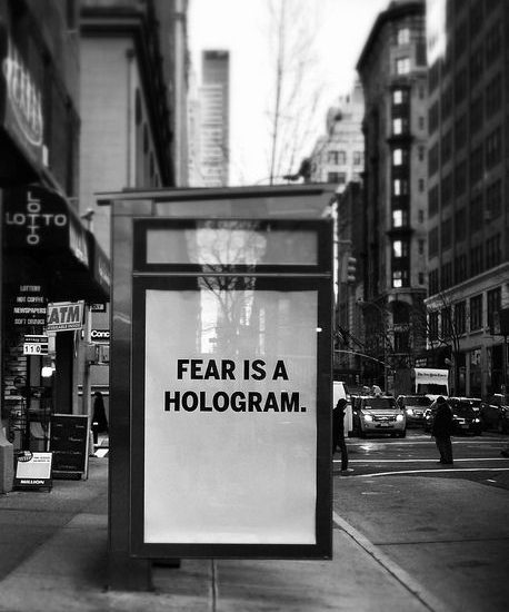 Panneau publicitaire. On peut y lire « Fear is a hologram » (« La peur est un hologram »).