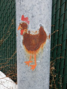 Tache de rouille sur un poteau en métal. Quelqu'un a utilisé de la peinture pour en faire un poulet.